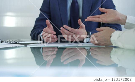 Business partners or lawyers dressed in blue are reviewing and discussing contract papers during a meeting, using a laptop and documents on a glass table. Businesspeople Business partners or lawyers dressed in blue are reviewing and discussing contract papers during a meeting, using a laptop and documents on a glass table. Businesspeople 123172008