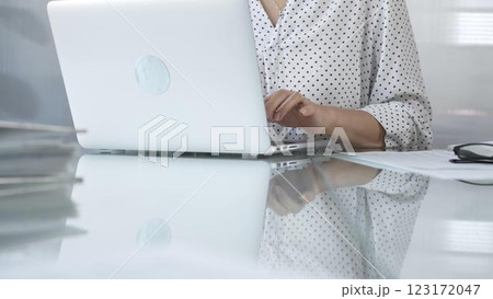 Businesswoman typing on laptop keyboard, preparing taxes and audit reports, with documents and eyeglasses on glass desk. Taxes, audit in business Businesswoman typing on laptop keyboard, preparing taxes and audit reports, with documents and eyeglasses on glass desk. Taxes, audit in business 123172047