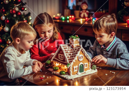Children sit at the table and decorate a gingerbread house Children sit at the table and decorate a gingerbread house 123173954