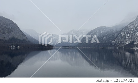 Serene Misty Mountain Lake Reflection Surrounded by Winter Snow-Covered Alpine Peaks in Hallstatt, Austria 123174323