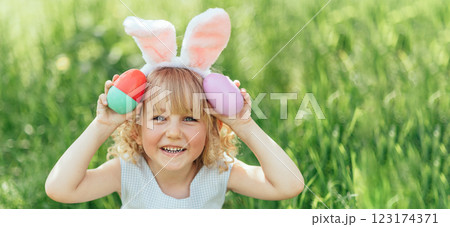 Easter egg hunt. Girl child Wearing Bunny Ears Running To Pick Up Egg In Garden. Easter tradition. Baby with basket full of colorful eggs. Easter egg hunt. Girl child Wearing Bunny Ears Running To Pick Up Egg In Garden. Easter tradition. Baby with basket full of colorful eggs. 123174371
