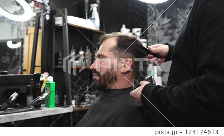 Professional barber trimming client's hair with precision, wielding scissors and comb inside contemporary grooming salon Professional barber trimming client's hair with precision, wielding scissors and comb inside contemporary grooming salon 123174613