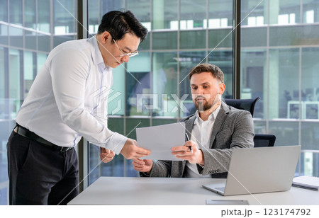 Two Businessmen Reviewing Documents in a Modern Office Environment 123174792