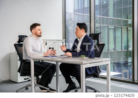 Businessmen Discussing Ideas at an Office Table in a Bright Modern Building 123174820