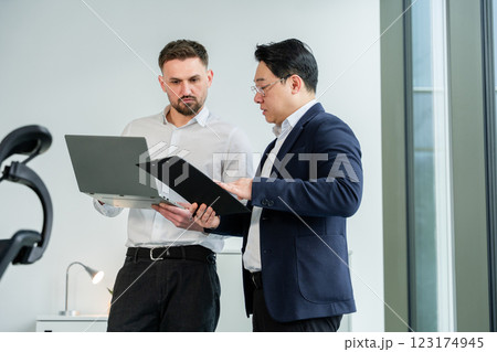 Two Business Professionals Collaborating and Analyzing Data in a Modern Office 123174945