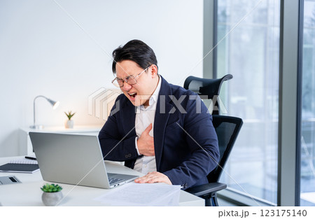 Upset Korean Businessman Experiencing Discomfort While Working on a Laptop 123175140