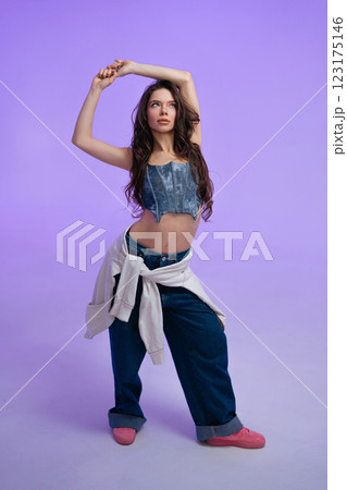 Young woman posing against a vibrant purple background in casual fashion Young woman posing against a vibrant purple background in casual fashion 123175146