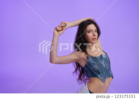 Model showcasing graceful pose against vibrant purple background Model showcasing graceful pose against vibrant purple background 123175151