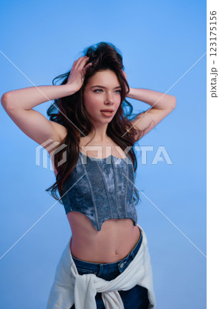 Young model poses with confidence in stylish denim outfit under studio lights 123175156