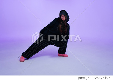 Stylish dancer performs dynamic pose in trendy streetwear on colorful backdrop 123175197