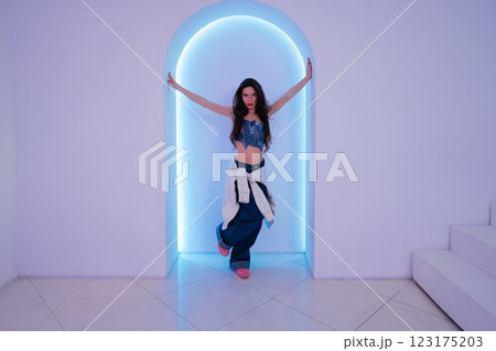 Model poses elegantly in neon-lit archway at trendy location 123175203