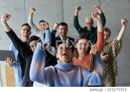 A diverse team of business professionals ecstatically celebrating their success in a modern office, expressing triumph and unity after achieving their goals 123175533