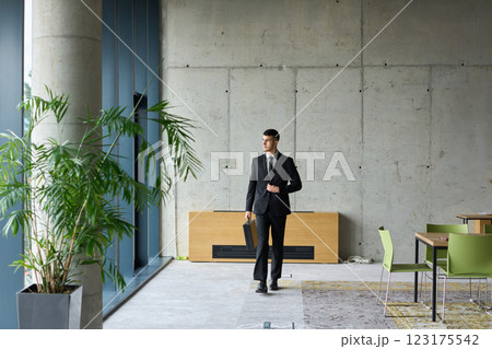 A determined businessman in a black suit confidently walks through the office, embodying professionalism and focus as he heads towards new challenges 123175542