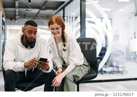 In a modern office African American businessman and businesswoman colleague, with her striking orange hair, engage in collaborative problem-solving sessions 123176017