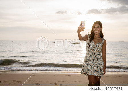Portrait of young woman on the beach using phone 123176214