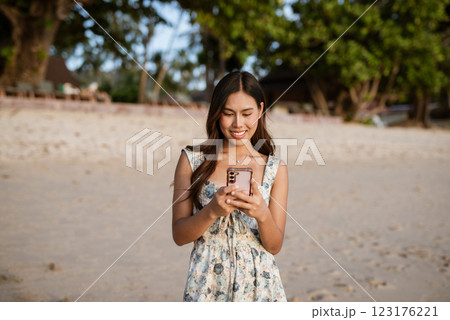 Portrait of young woman on the beach using phone Portrait of young woman on the beach using phone 123176221