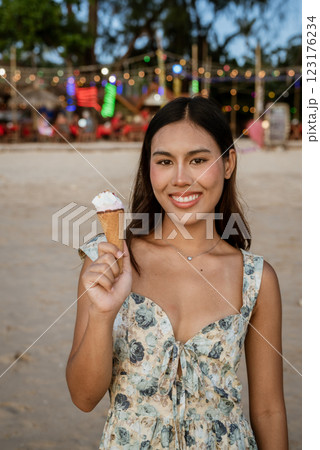 Young woman on the beach eating ice cream 123176234
