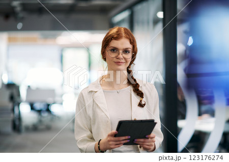 A business woman with orange hair self confident, fully engaged in working on a tablet, exuding creativity, ambition and a lively sense of individuality 123176274