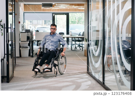 In a large modern corporation, a determined businessman in a wheelchair navigates through a hallway, embodying empowerment and inclusivity in the corporate world 123176408