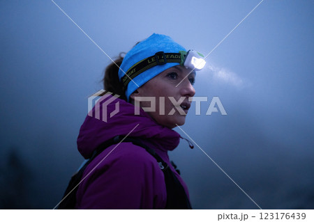 Determined Woman Trail Running at Night, Illuminated by a Headlamp in the Mountain Wilderness. 123176439