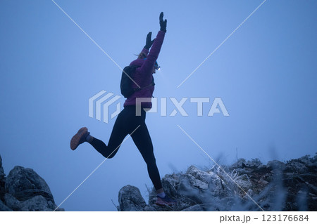 Determined Woman Trail Running at Night, Illuminated by a Headlamp in the Mountain Wilderness. 123176684