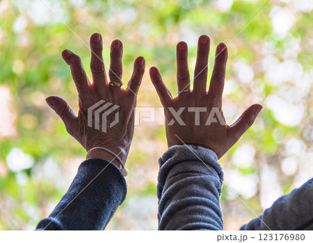 Hands leaning on the window of people in confinement, looking at the street, loneliness, sadness	 123176980