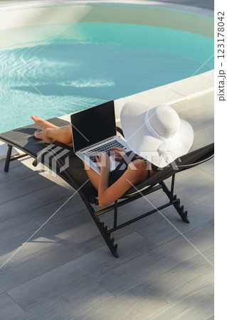 Woman working on laptop by the pool 123178042