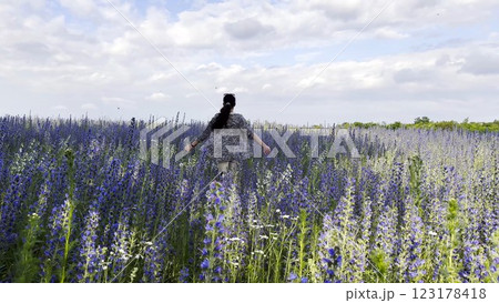 Young girl running through beautiful purple flowers field at summer day. Happy woman having fun while jogging among violet blossoms at meadow. Beautiful nature background. Freedom concept. Slow mo Young girl running through beautiful purple flowers field at summer day. Happy woman having fun while jogging among violet blossoms at meadow. Beautiful nature background. Freedom concept. Slow mo 123178418