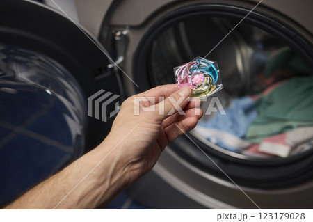 Using Laundry Detergent Pods While Doing Laundry in the Washing Machine with Clothes 123179028