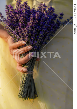woman poses in lavender field at sunset. Happy woman in yellow dress holds lavender bouquet. Aromatherapy concept, lavender oil, photo session in lavender 123179641