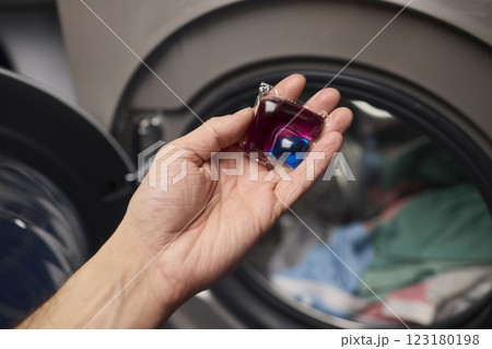 Using Laundry Detergent Pods While Doing Laundry in the Washing Machine with Clothes 123180198