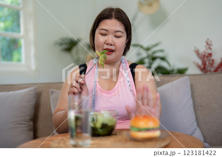 Overweight woman choosing salad over burger for healthy weight loss. 123181422