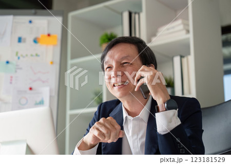 Elderly businessman discussing data insights on the phone in a modern office 123181529