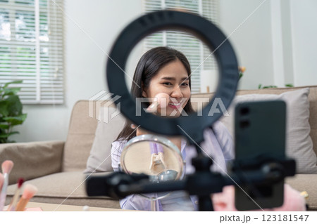 Asian woman smiling while using blush in home makeup routine 123181547