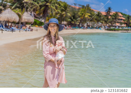 A mother introduces her newborn baby to the sea for the first time, holding her little one close as they experience the ocean breeze and the soothing sound of waves. A heartwarming moment of love 123181682