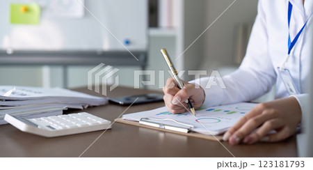 Accountant analyzing financial reports with pen and calculator in a modern office setting. Accountant analyzing financial reports with pen and calculator in a modern office setting. 123181793