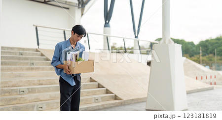 Man departing from workplace with a box of belongings, representing a significant career transition. Man departing from workplace with a box of belongings, representing a significant career transition. 123181819