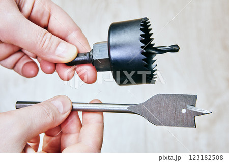 Hand holding hole saw and spade drill bit. Hand holding hole saw and spade drill bit. 123182508