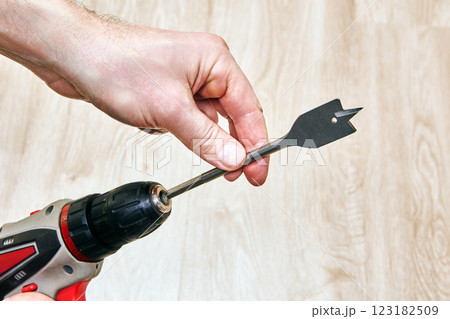 Cordless drill with spade bit held by hand. Cordless drill with spade bit held by hand. 123182509