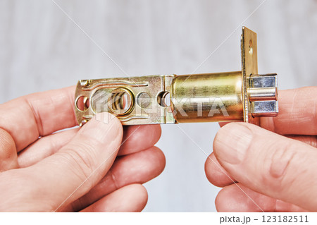 Hands holding brass tubular door latch with mounting plate. Hands holding brass tubular door latch with mounting plate. 123182511
