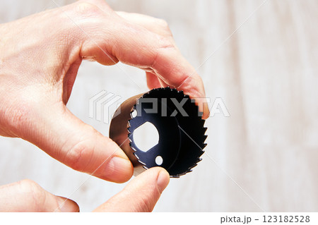 Hand holding circular hole saw with serrated cutting edges. Hand holding circular hole saw with serrated cutting edges. 123182528