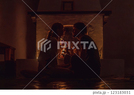Family bonding by the fireplace during cozy winter evening. Warm and peaceful family moment indoors. Togetherness, love, and relaxation concept. A warm and inviting scene featuring a lit fireplace 123183031
