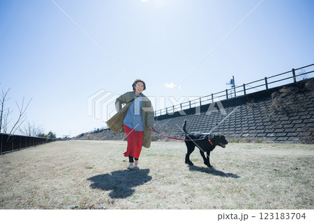 河川敷で散歩を楽しむ女性と楽しそうな大型犬ワンちゃん 123183704