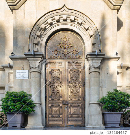 Holy Myrrhbearers Cathedral entrance in Baku, Azerbaijan. Metal double doors with intricate designs lead to stone facade Holy Myrrhbearers Cathedral entrance in Baku, Azerbaijan. Metal double doors with intricate designs lead to stone facade 123184487