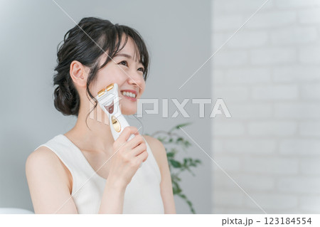 美顔器を使ってホームエステ・リフトアップ・マッサージする笑顔のアジア人女性 123184554