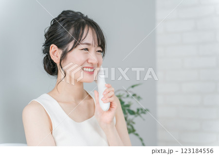 美顔器を使ってホームエステ・リフトアップ・マッサージする笑顔のアジア人女性 123184556