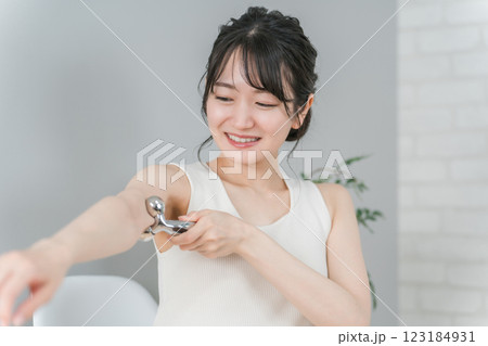 マッサージローラーで二の腕をボディケアするアジア人女性 マッサージローラーで二の腕をボディケアするアジア人女性 123184931