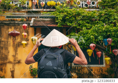 back of Asian male traveler tourist in traditional vietnamese hat on street in old town in Hoi An city in Vietnam in Asia 123186833