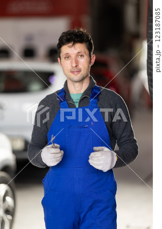 Adult man mechanic in uniform posing in car service station 123187085