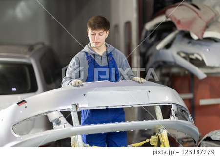 Service station young man employee works in repair box, department Service station young man employee works in repair box, department 123187279